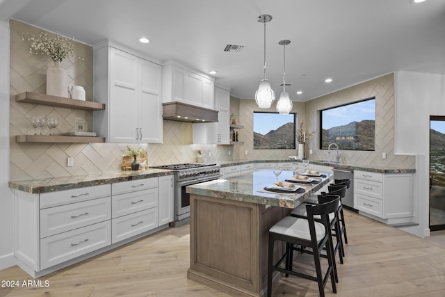 kitchen with white cabinets, stainless steel appliances, a kitchen island, and dark stone counters