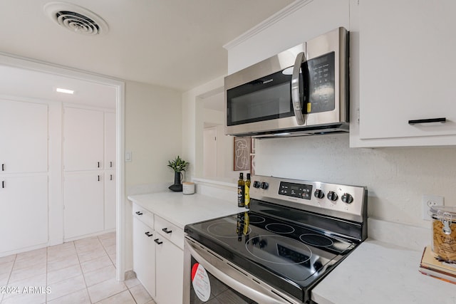 kitchen with appliances with stainless steel finishes, light tile patterned floors, and white cabinetry