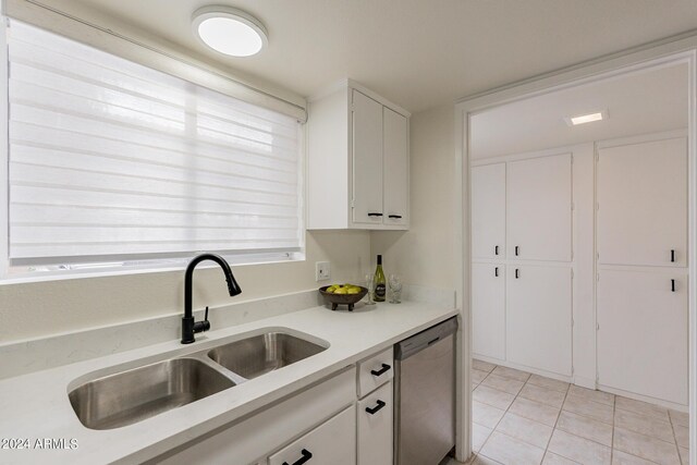 kitchen with light tile patterned floors, sink, dishwasher, and white cabinetry