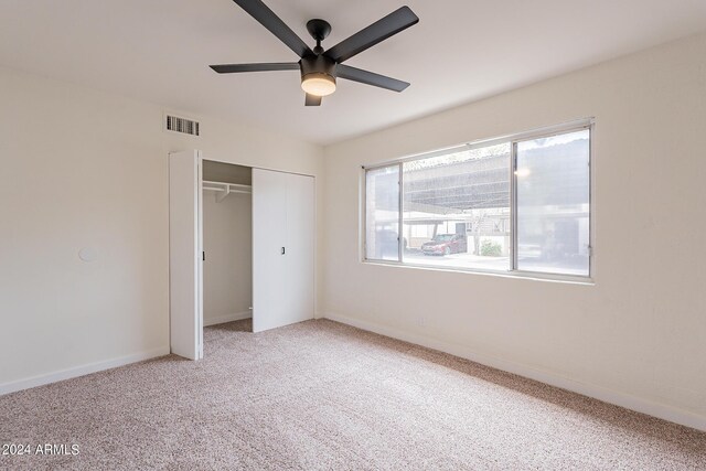 unfurnished bedroom featuring ceiling fan, light carpet, and a closet