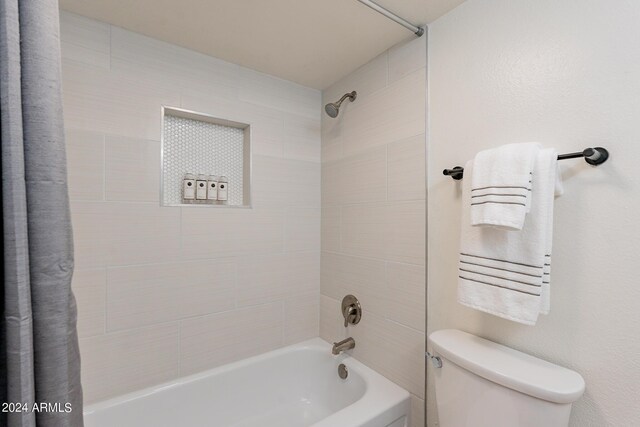 bathroom featuring shower / bathtub combination with curtain and toilet