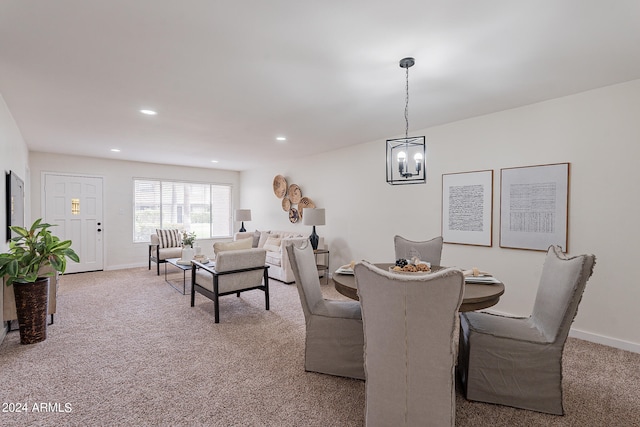 dining space featuring light carpet and an inviting chandelier