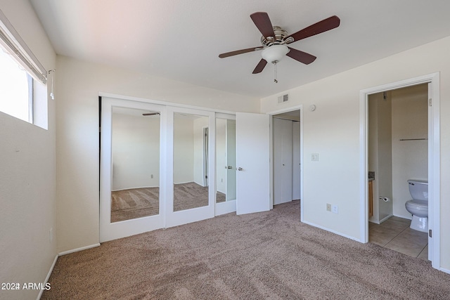 unfurnished bedroom featuring two closets, light carpet, french doors, ceiling fan, and ensuite bathroom