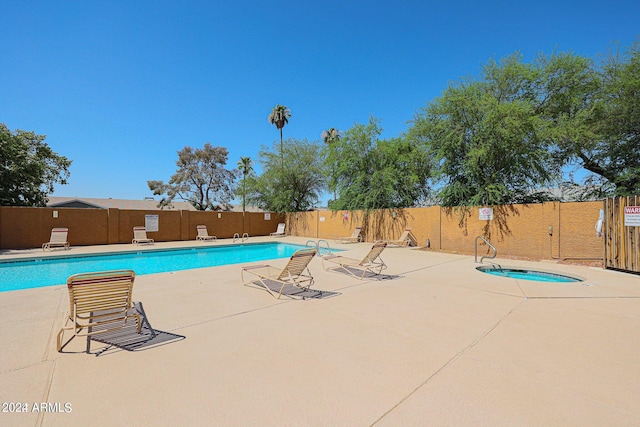 view of pool with a hot tub and a patio