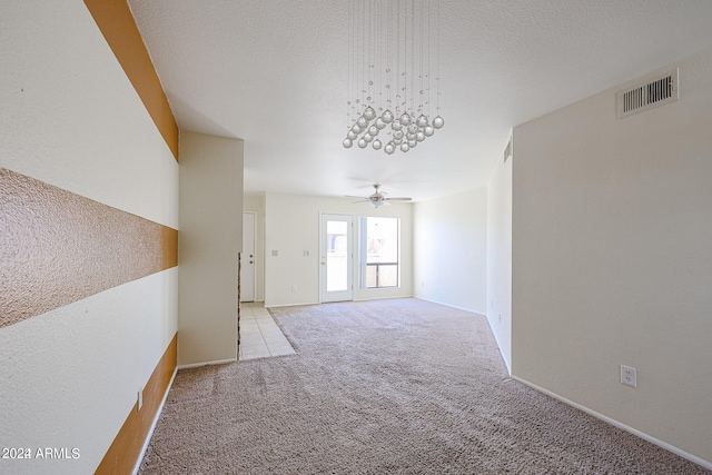 carpeted spare room featuring ceiling fan and a textured ceiling