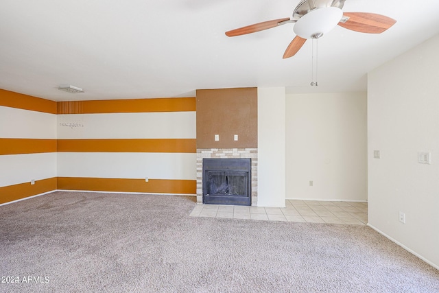 unfurnished living room featuring ceiling fan, a tile fireplace, and light carpet