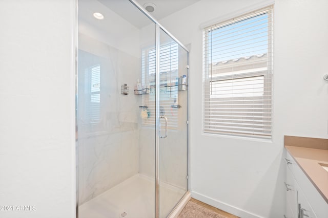 bathroom featuring a shower with door and vanity