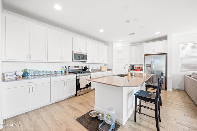 kitchen featuring white cabinets, sink, a breakfast bar area, an island with sink, and stainless steel appliances