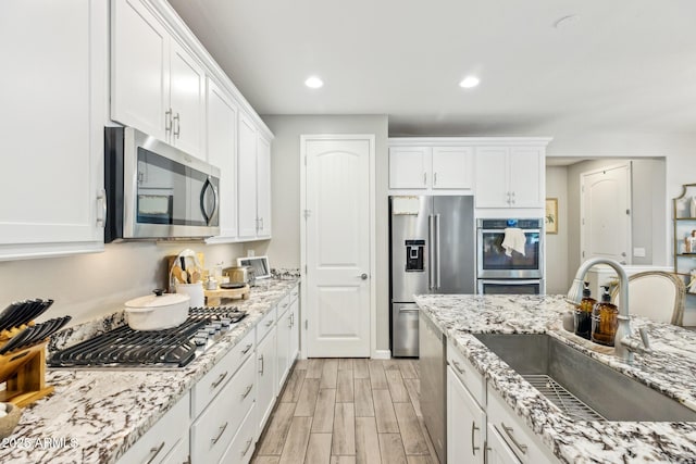 1941 W Yellowstone Way, Chandler, AZ 85248 - kitchen with appliances with stainless steel finishes, a sink, white cabinets, light wood-style flooring, and recessed lighting