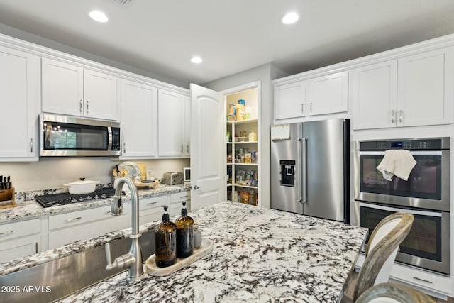 1941 W Yellowstone Way, Chandler, AZ 85248 - kitchen with stainless steel appliances, white cabinetry, a sink, light stone counters, and recessed lighting