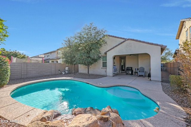 view of swimming pool featuring ceiling fan and a patio