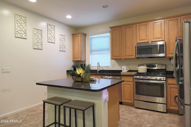 kitchen with a kitchen breakfast bar, a center island, light tile patterned floors, and stainless steel appliances