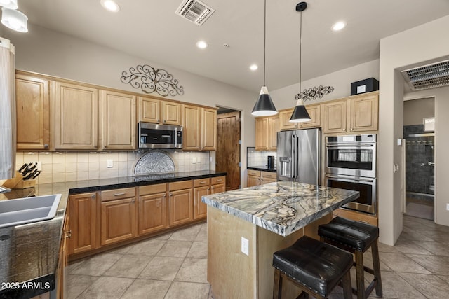 14007 E Lupine Ave, Scottsdale, AZ 85259 - kitchen with appliances with stainless steel finishes, decorative backsplash, a kitchen island, a breakfast bar area, and decorative light fixtures