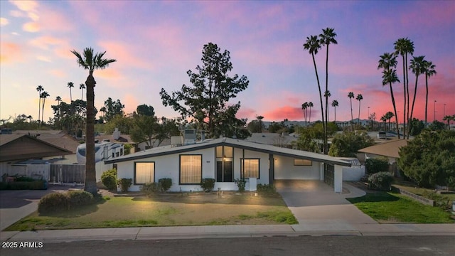 mid-century inspired home with a carport, fence, concrete driveway, and a front yard