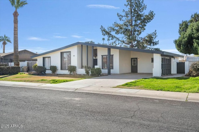 mid-century modern home with an attached carport, fence, driveway, and stucco siding