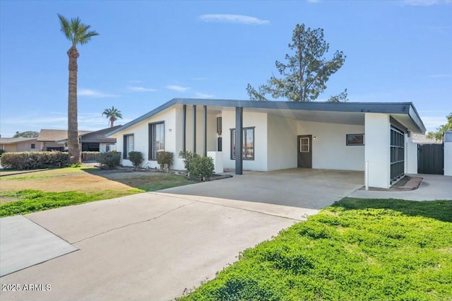 view of front of house featuring driveway, an attached carport, a front yard, and stucco siding