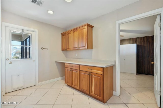 kitchen with brown cabinets, light tile patterned floors, visible vents, and light countertops