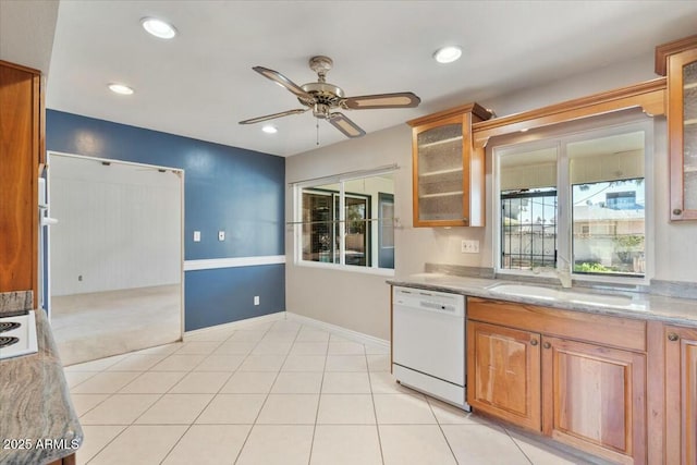 kitchen with light tile patterned floors, a sink, dishwasher, brown cabinetry, and glass insert cabinets