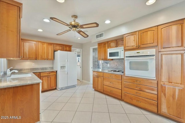 kitchen featuring white appliances, visible vents, brown cabinetry, and a sink