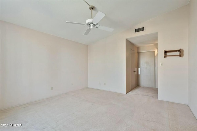 empty room featuring light colored carpet, lofted ceiling, visible vents, and a ceiling fan