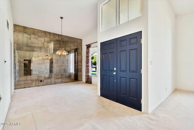 carpeted entrance foyer featuring a chandelier and a towering ceiling