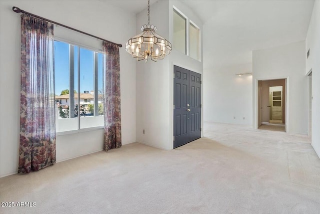 empty room featuring a high ceiling, carpet flooring, and a notable chandelier