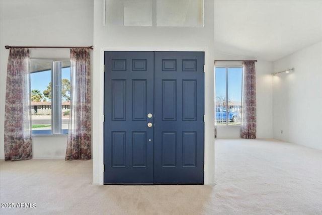 entryway with light carpet and vaulted ceiling