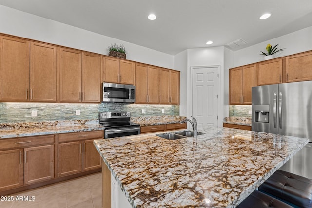 kitchen with a kitchen island with sink, sink, and appliances with stainless steel finishes