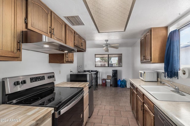 kitchen with white microwave, under cabinet range hood, a sink, visible vents, and stainless steel range with electric stovetop