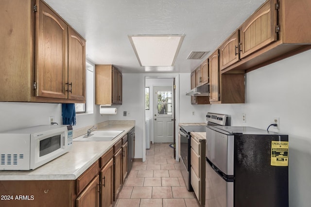 kitchen with under cabinet range hood, a sink, visible vents, light countertops, and appliances with stainless steel finishes