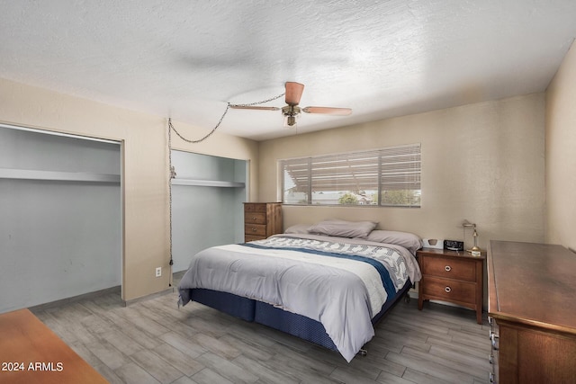 bedroom with a textured ceiling, a ceiling fan, and wood finished floors