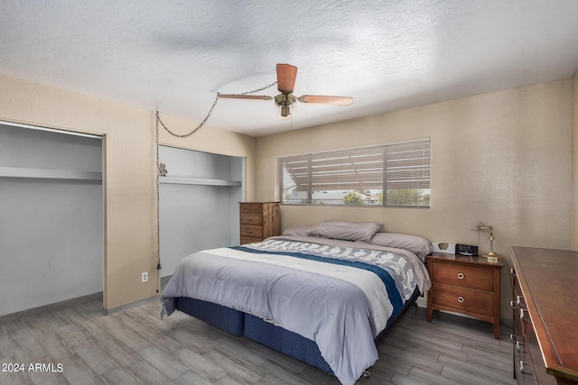 bedroom featuring multiple closets, ceiling fan, a textured ceiling, and wood finished floors