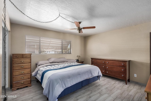 bedroom with a textured ceiling, ceiling fan, and wood finished floors