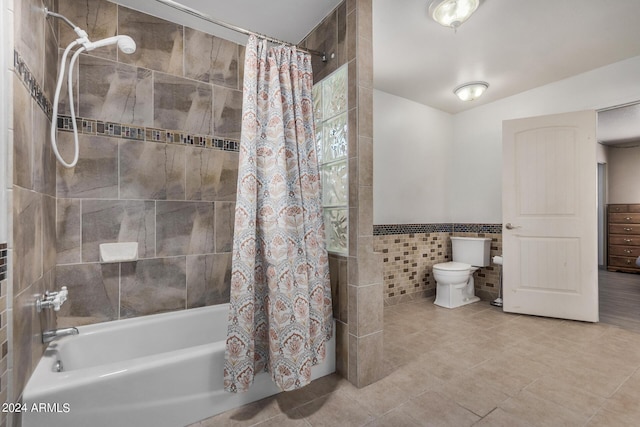 bathroom featuring tile walls, shower / bath combination with curtain, toilet, wainscoting, and tile patterned floors