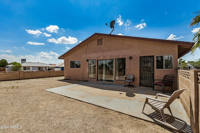 rear view of house featuring fence, a patio, and stucco siding