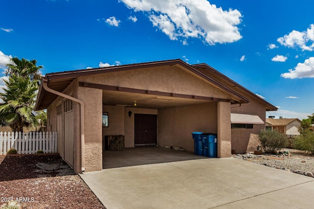 view of front facade with a carport, fence, concrete driveway, and stucco siding