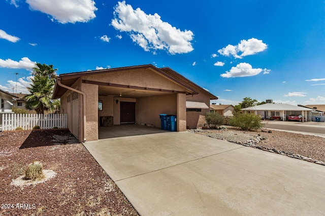 view of front of house with a carport, driveway, fence, and stucco siding