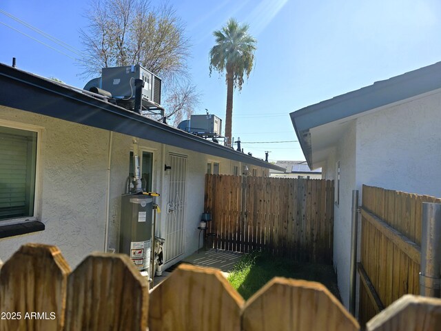 4450 N Longview Ave, Phoenix, AZ 85014 - view of side of home featuring stucco siding, water heater, and fence