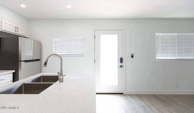 4450 N Longview Ave, Phoenix, AZ 85014 - kitchen featuring freestanding refrigerator, wood finished floors, a sink, light countertops, and white cabinets