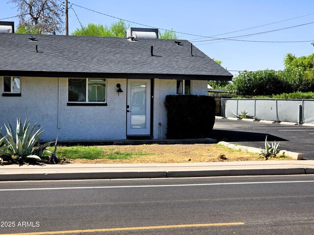 4450 N Longview Ave, Phoenix, AZ 85014 - bungalow-style home with roof with shingles, stucco siding, and fence