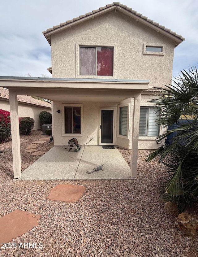 back of house with a tile roof, a patio area, and stucco siding