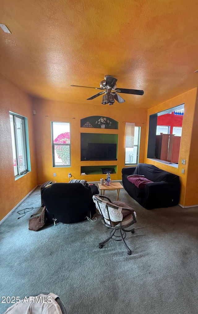 carpeted living area featuring a ceiling fan and a textured ceiling