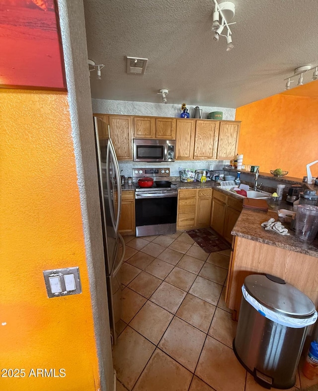 kitchen featuring light tile patterned floors, visible vents, appliances with stainless steel finishes, a textured ceiling, and a sink