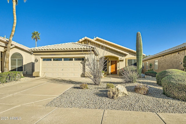 view of front of property featuring a garage, driveway, a tile roof, and stucco siding