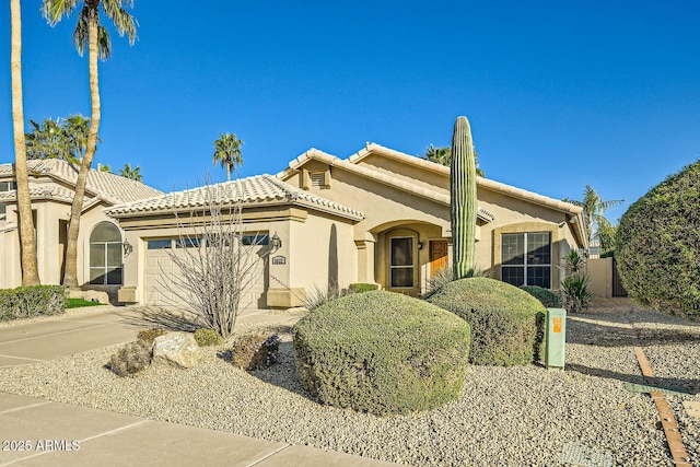 mediterranean / spanish house featuring a tiled roof, concrete driveway, an attached garage, and stucco siding