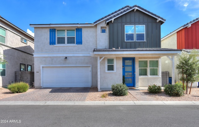 view of front facade with stucco siding, board and batten siding, decorative driveway, and a garage