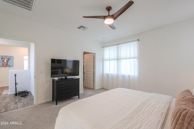 bedroom with visible vents, light carpet, baseboards, and a ceiling fan