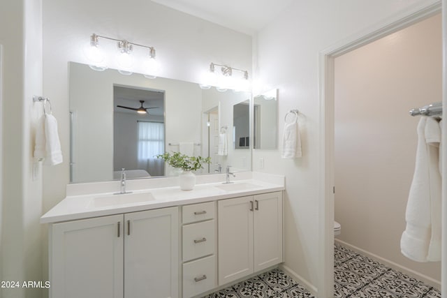 bathroom with double vanity, toilet, baseboards, and a sink