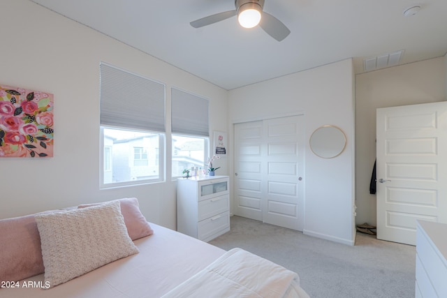 bedroom featuring visible vents, light colored carpet, a closet, and a ceiling fan