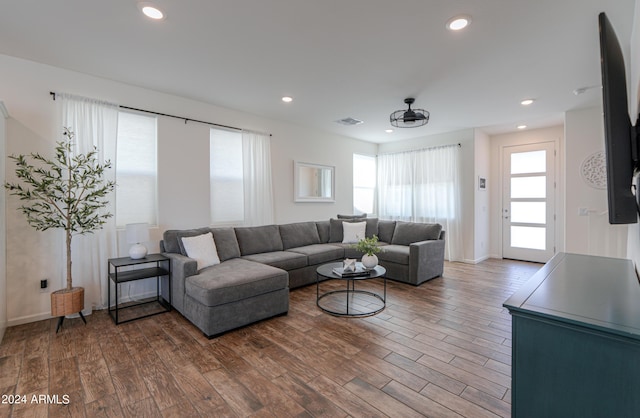 living room with recessed lighting, visible vents, baseboards, and wood finished floors